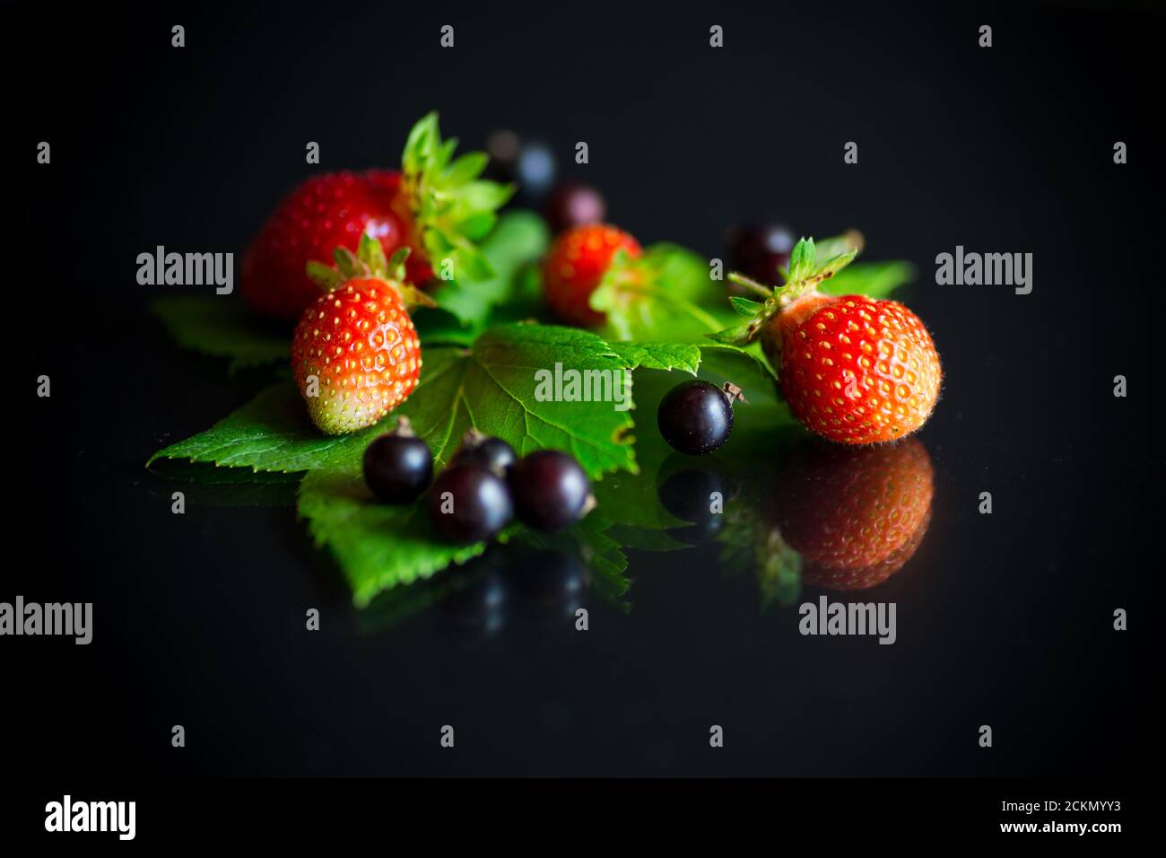 ripe red strawberries and berries of black currant Stock Photo
