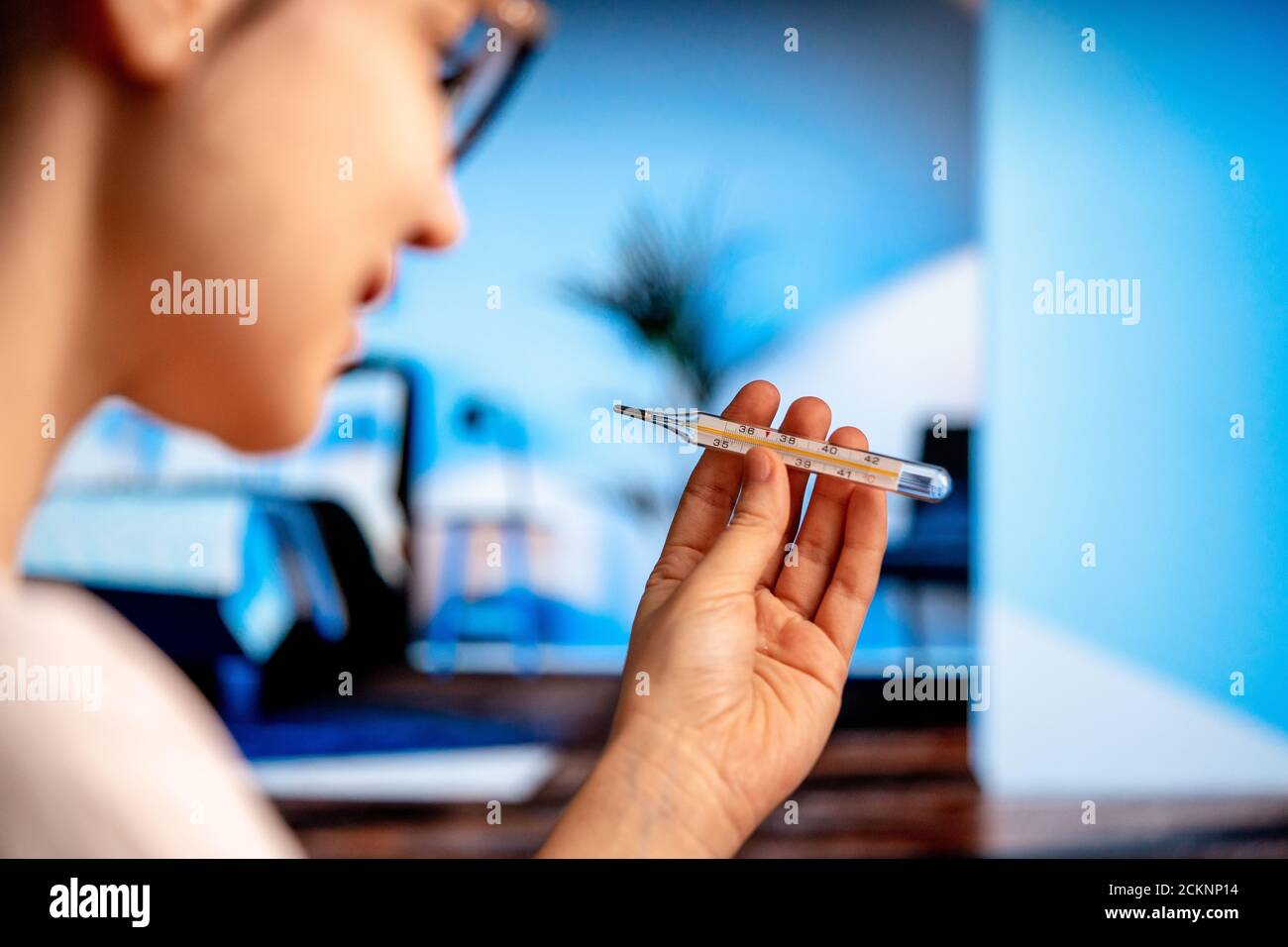 Young Woman Checking Body Temperature Using Mercury Thermometer for