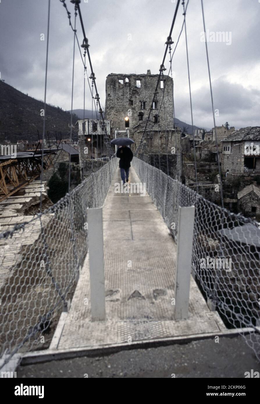 6th December 1995 During the war in Bosnia: a man crosses a cable footbridge that replaced the Stari Most (Old Bridge), over the Neretva River in Mostar. Stock Photo