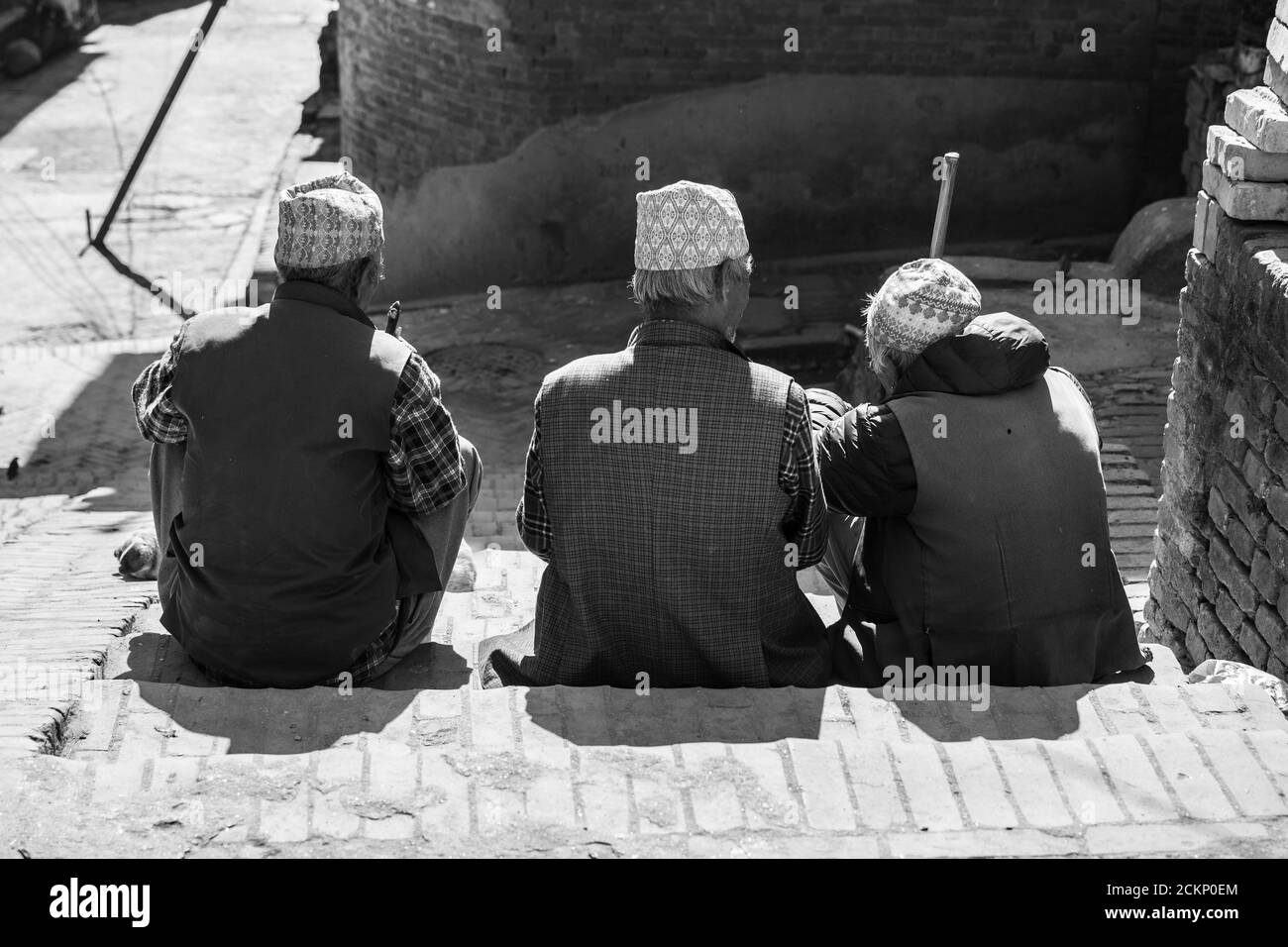 Bhaktapur, Kathmandu, Nepal - December 23, 2019: Three unidentified men sits and talks on the side of the street in some stairs on December 23, 2019 Stock Photo