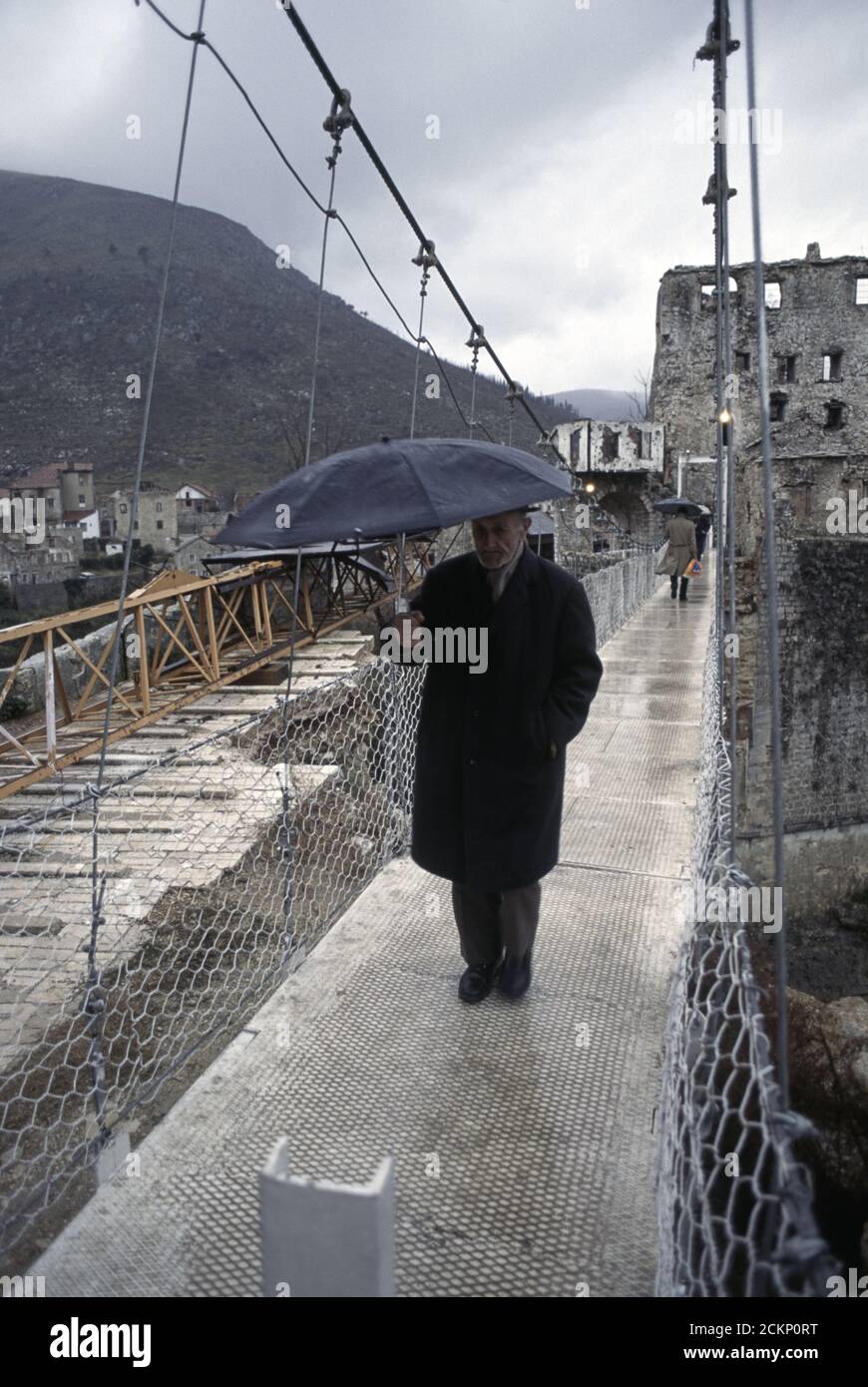 6th December 1995 During the war in Bosnia: people cross a cable footbridge that replaced the Stari Most (Old Bridge), over the Neretva River in Mostar. Stock Photo