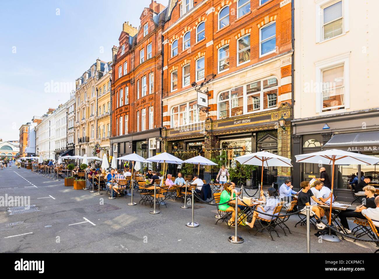 Al fresco roadside lunchtime socialising, dining, eating and drinking in pedestrianised Henrietta Street, Covent Garden, London WC2 on a sunny day Stock Photo