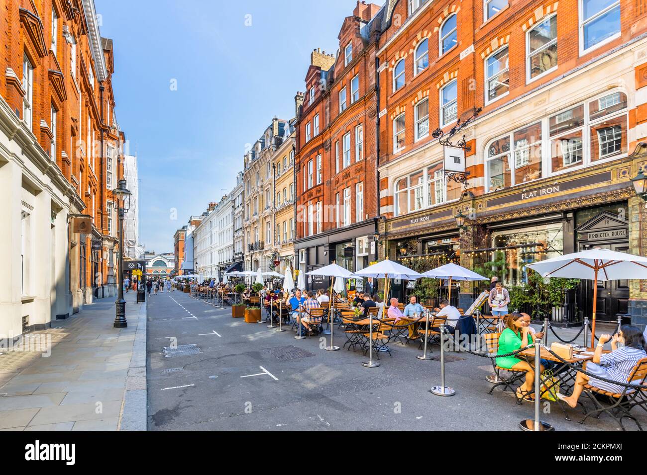 Al fresco roadside lunchtime socialising, dining, eating and drinking in pedestrianised Henrietta Street, Covent Garden, London WC2 on a sunny day Stock Photo