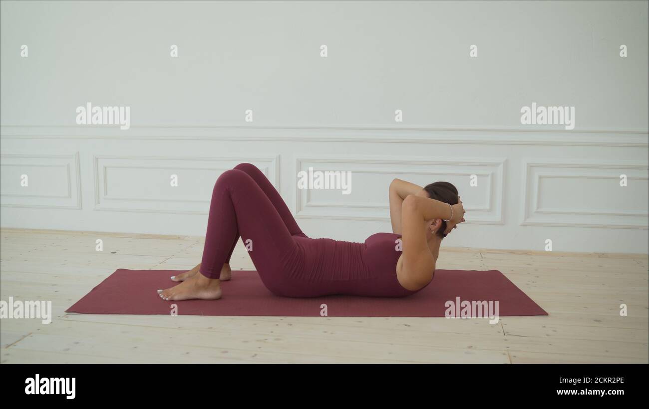 Slim woman training on yoga mat on wooden promenade Stock Photo by