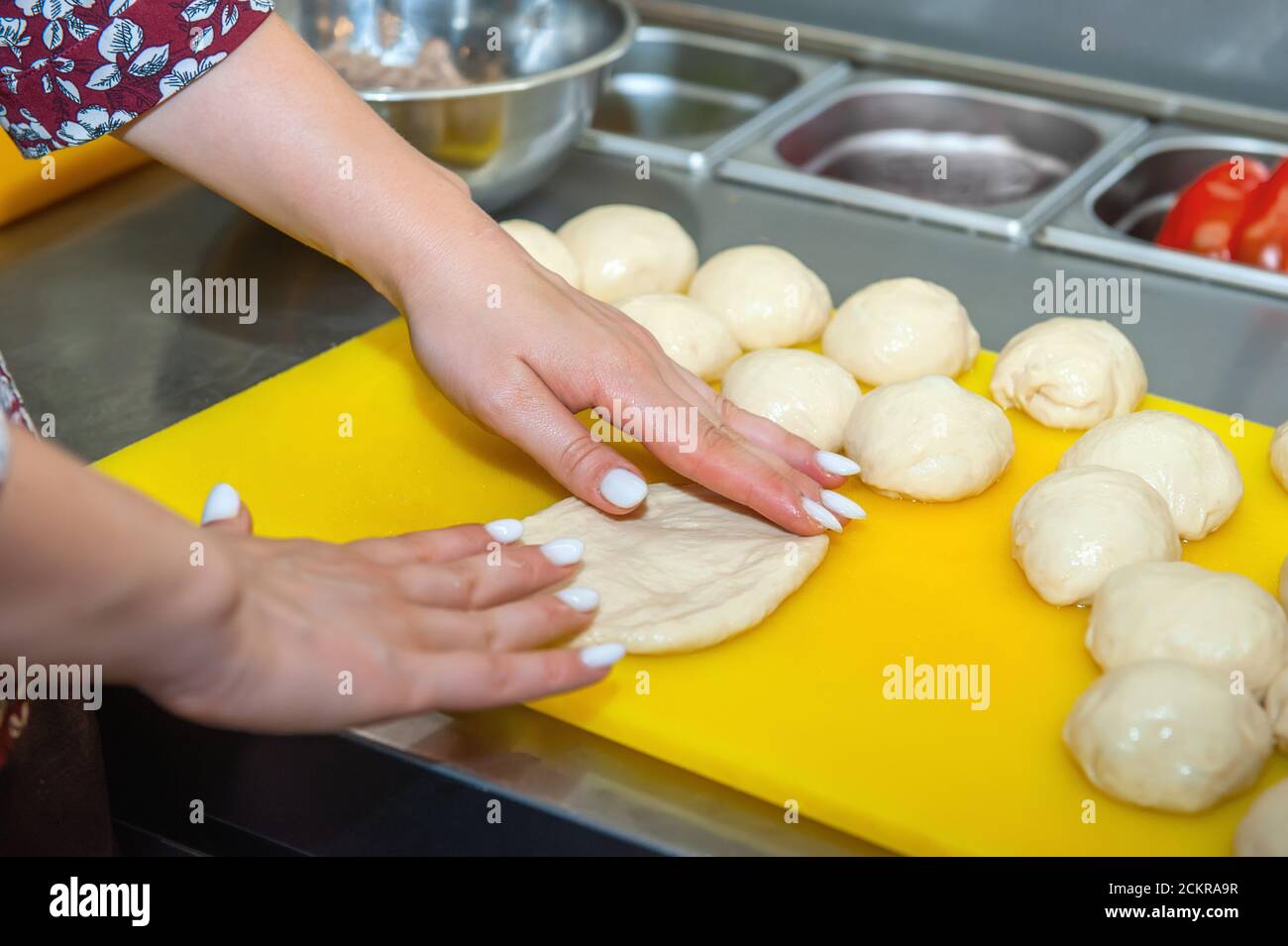 Woman using a dough cutter to divide the naan bread dough into six equal  portions which are flattened and baked. Bakers and pas Stock Photo - Alamy