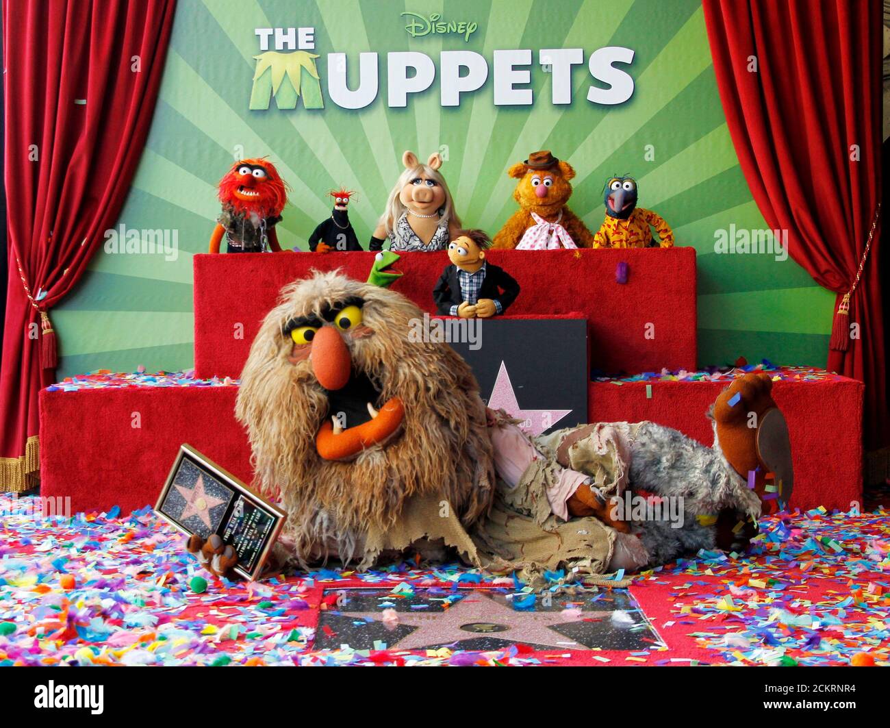 Muppet character Sweetums holds a commemorative plaque as he lies beside  the newly unveiled Muppets star as other Mupetts background (L-R) Animal,Pepe,  Miss Piggy, Fozzie and Gonzo and bottom row Kermit and