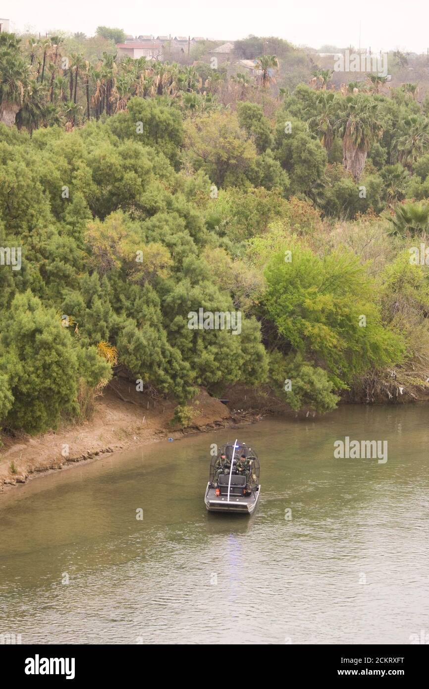 Laredo, TX  February 20, 2009: A U.S. Border Patrol airboat with two agents aboard patrols the Rio Grande River, looking west through downtown Laredo. The United States border is shown on the left.         ©Bob Daemmrich Stock Photo