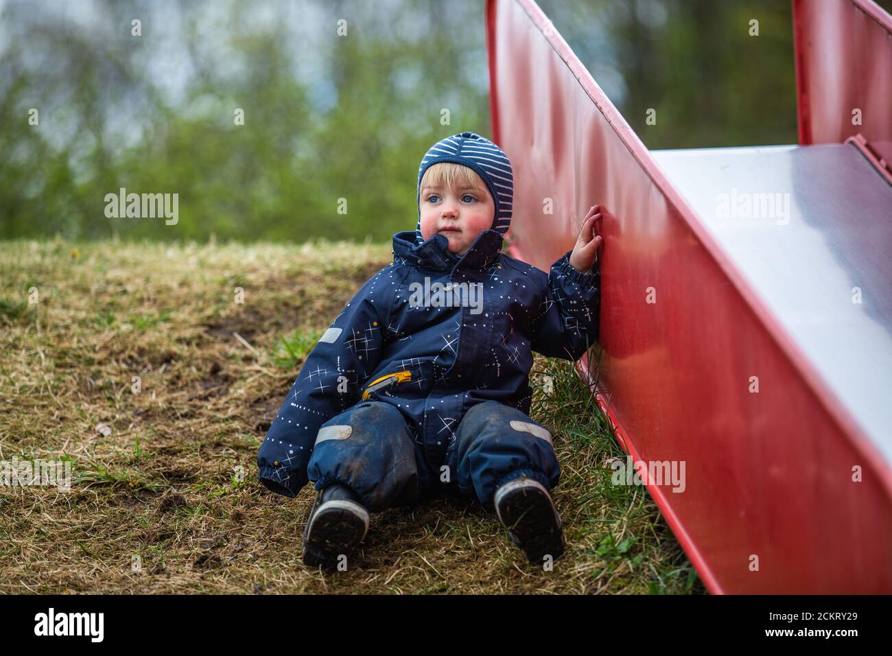 Young boy wearing a puddle suit leaning on a slide Stock Photo Alamy
