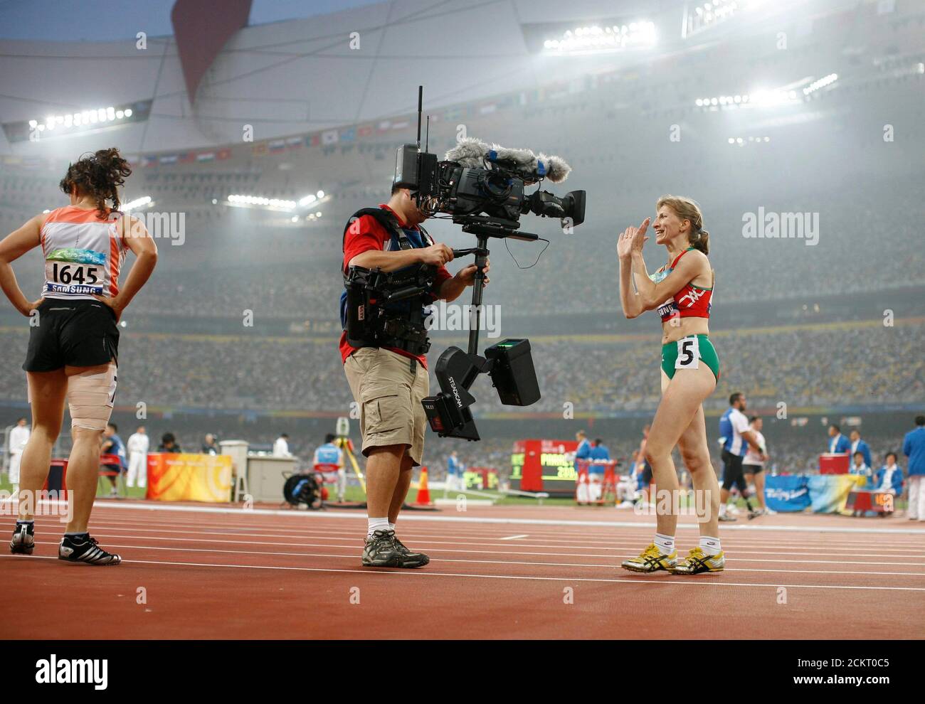 Beijing, China, September 15, 2008: Scenes from an evening session of the Paralympic Games at the Olympic Stadium, known as the Bird's Nest.  Track athlete Volha Zinkevich of Belarus (r) smiles for the Chinese network cameraman with a Steadicam after a semi-final victory.   ©Bob Daemmrich Stock Photo