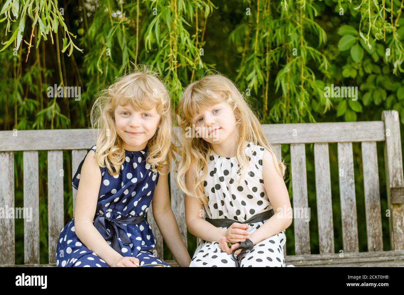 two beautiful blond girls sittings in the bench Stock Photo