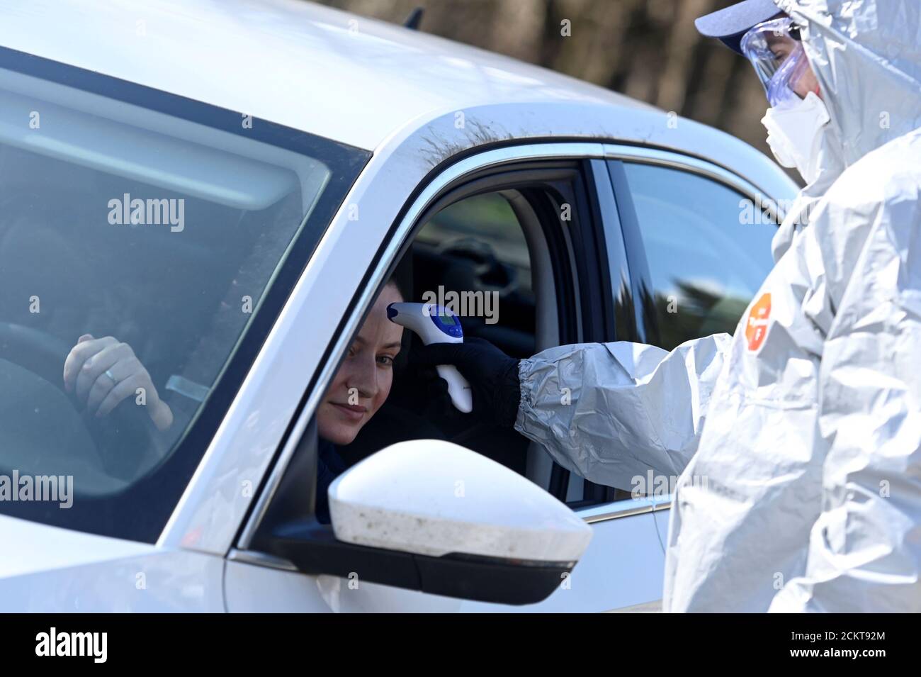 A police officer in a protective suit checks the temperature of a person inside a car at Slovak-Czech border in Drietoma crossing, Slovakia, March 13, 2020. REUTERS/Radovan Stoklasa Stock Photo