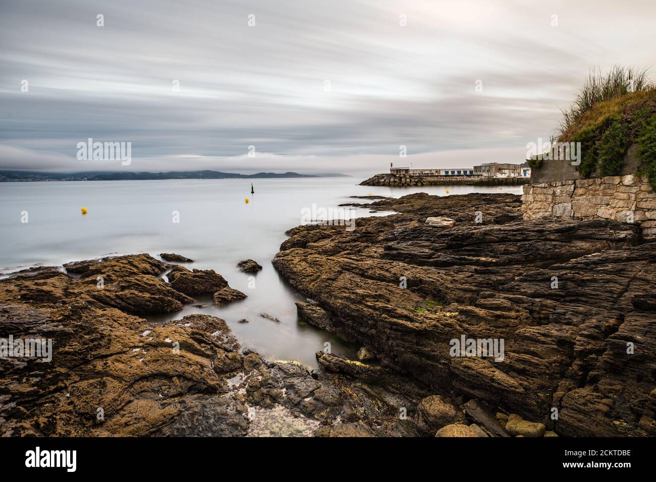 Rocks and small lighthouse on a stormy evening in the Rias Baixas in Galicia, Spain. Long exposure. Stock Photo