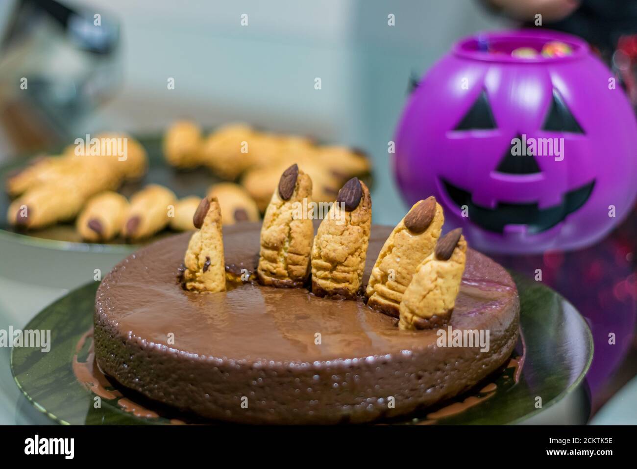 Halloween chocolate cake celebration with cuted cookies fingers and background purple pumpkin and plate of fingers Stock Photo