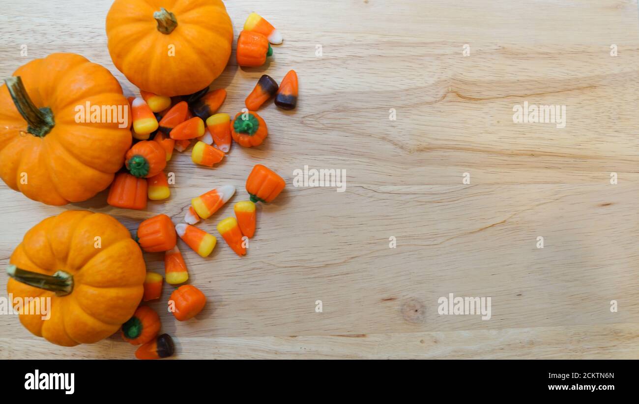 Miniature pumpkins and autumn mix candy corn on a wooden background. Template with copy space for autumn or Halloween season Stock Photo