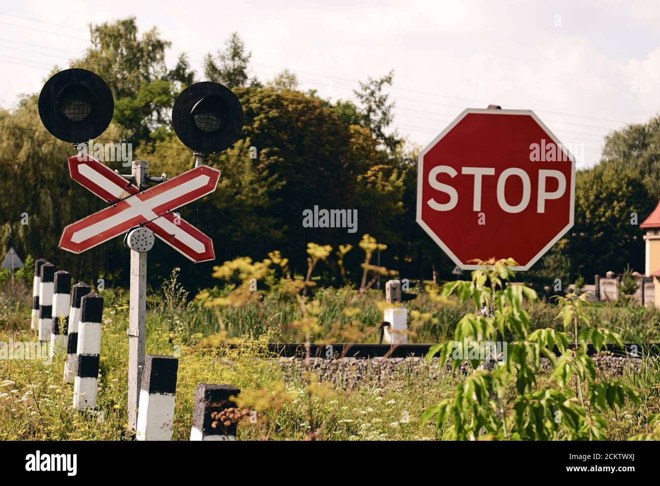 Railroad crossing with a Stop sign. Train rails in country landscape. Railroad tracks at sunset time. Local travel concept Stock Photo