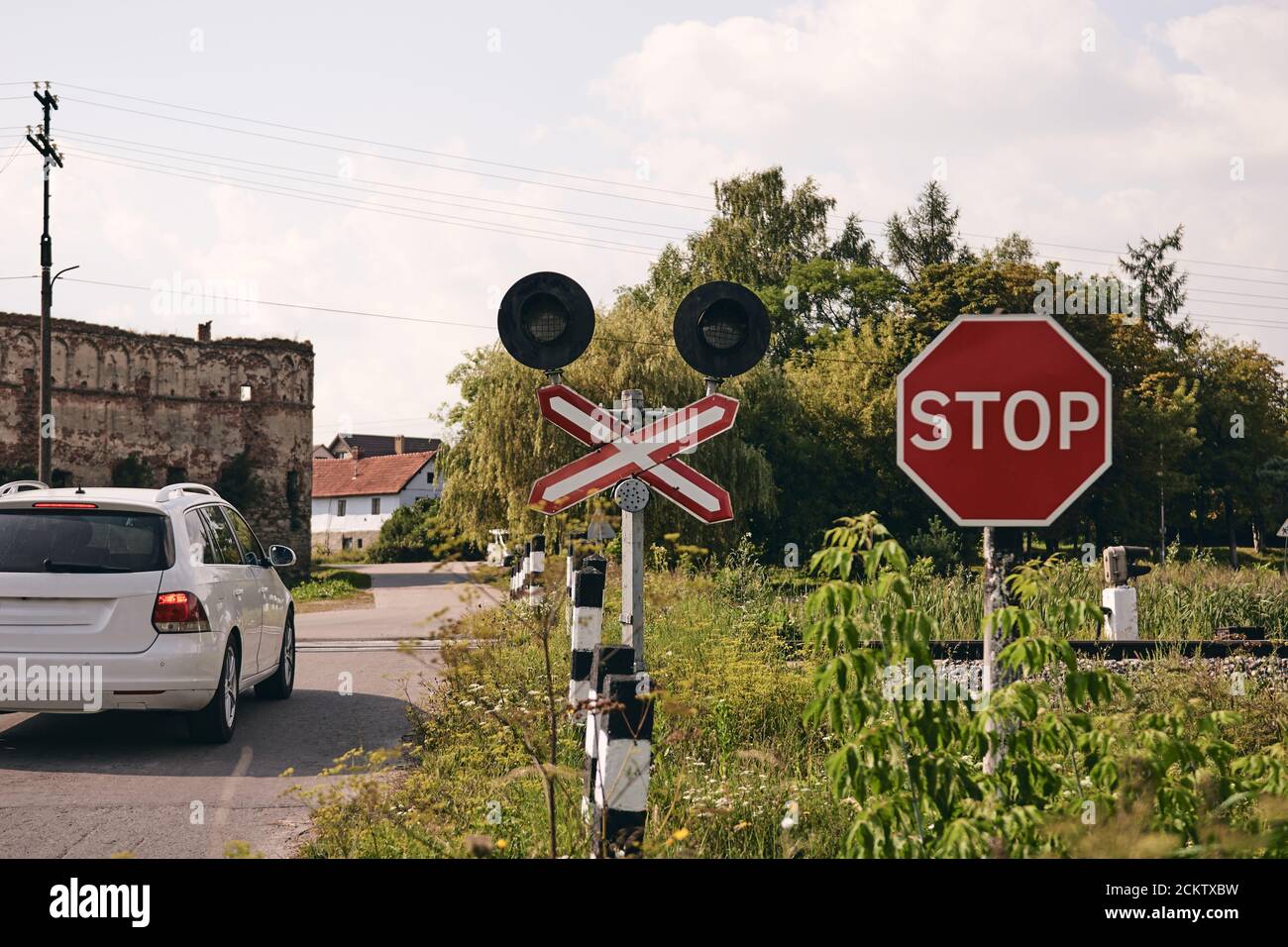 A car crossing Railroad with a Stop sign. Train rails in country landscape. Railroad tracks at