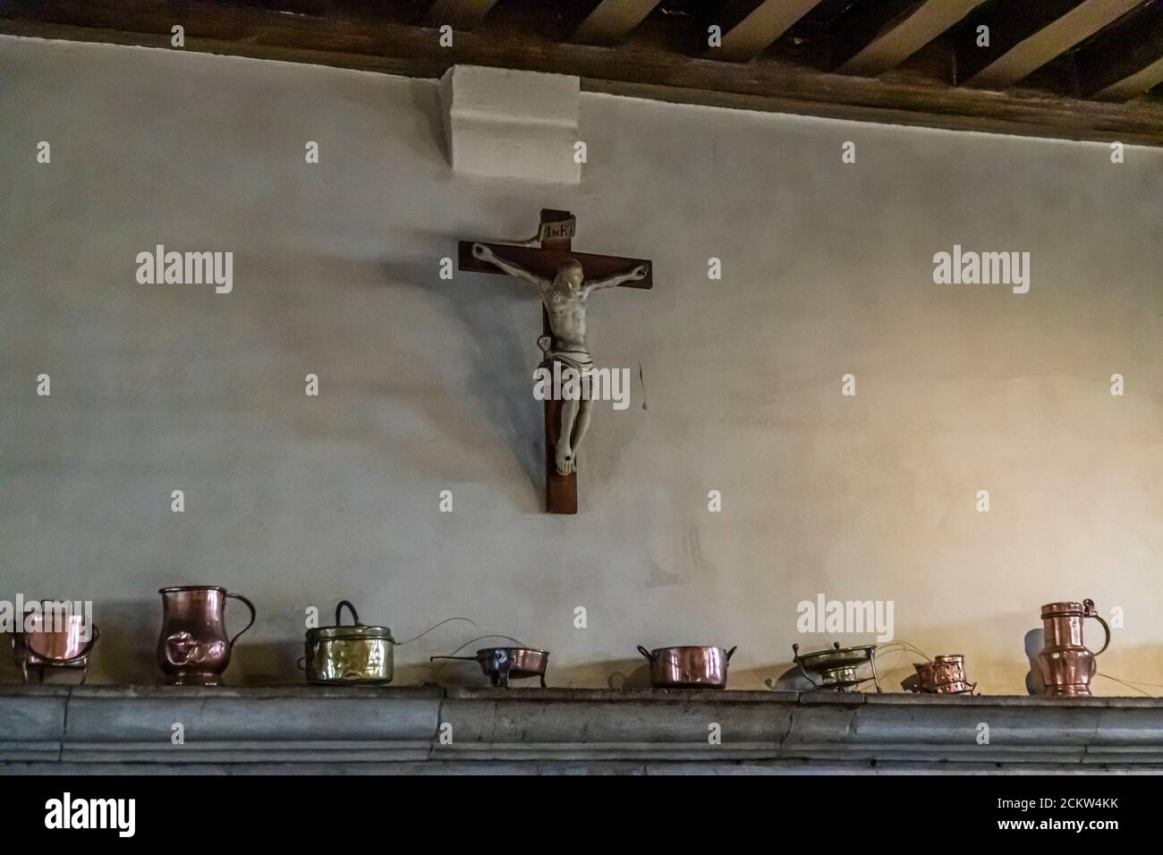 A christian cross hangs over a mantelpiece full of copper vessels in the Hotel-Dieu, Beaune, France Stock Photo