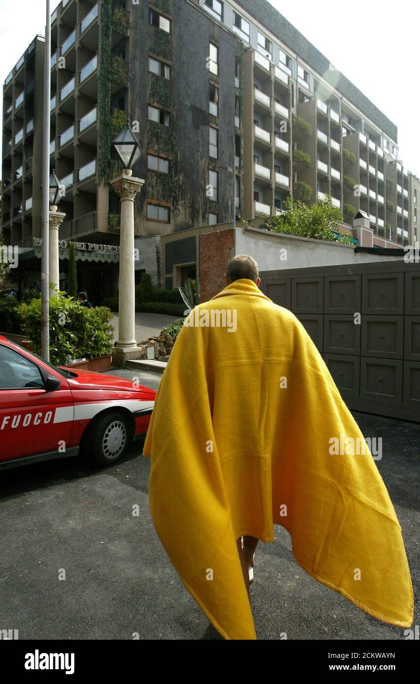 A guest at the Hotel Parco dei Principi, in Rome walks in front of the building draped in a yellow blanket after a fire started at around 5 a.m. local time (0300 GMT) in a room on the third floor May 1, 2004. A Canadian couple died in the fire and an American died after throwing himself off one of the balconies of the five-star hotel trying to escape the flames. Among the guest were several tennis player in town for the Rome Open Tennis Master next week. REUTERS/Max Rossi  MR/WS Stock Photo