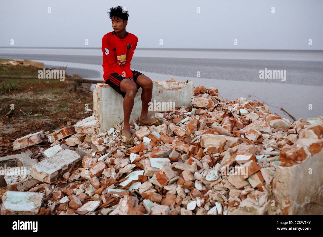 Myo Zaw, 15, sits at the ruins of a monastery after the riverbank it was located on collapsed into the water in Ta Dar U village, Bago, Myanmar, February 5, 2020. Photo taken on February 5, 2020. REUTERS/Ann Wang Stock Photo