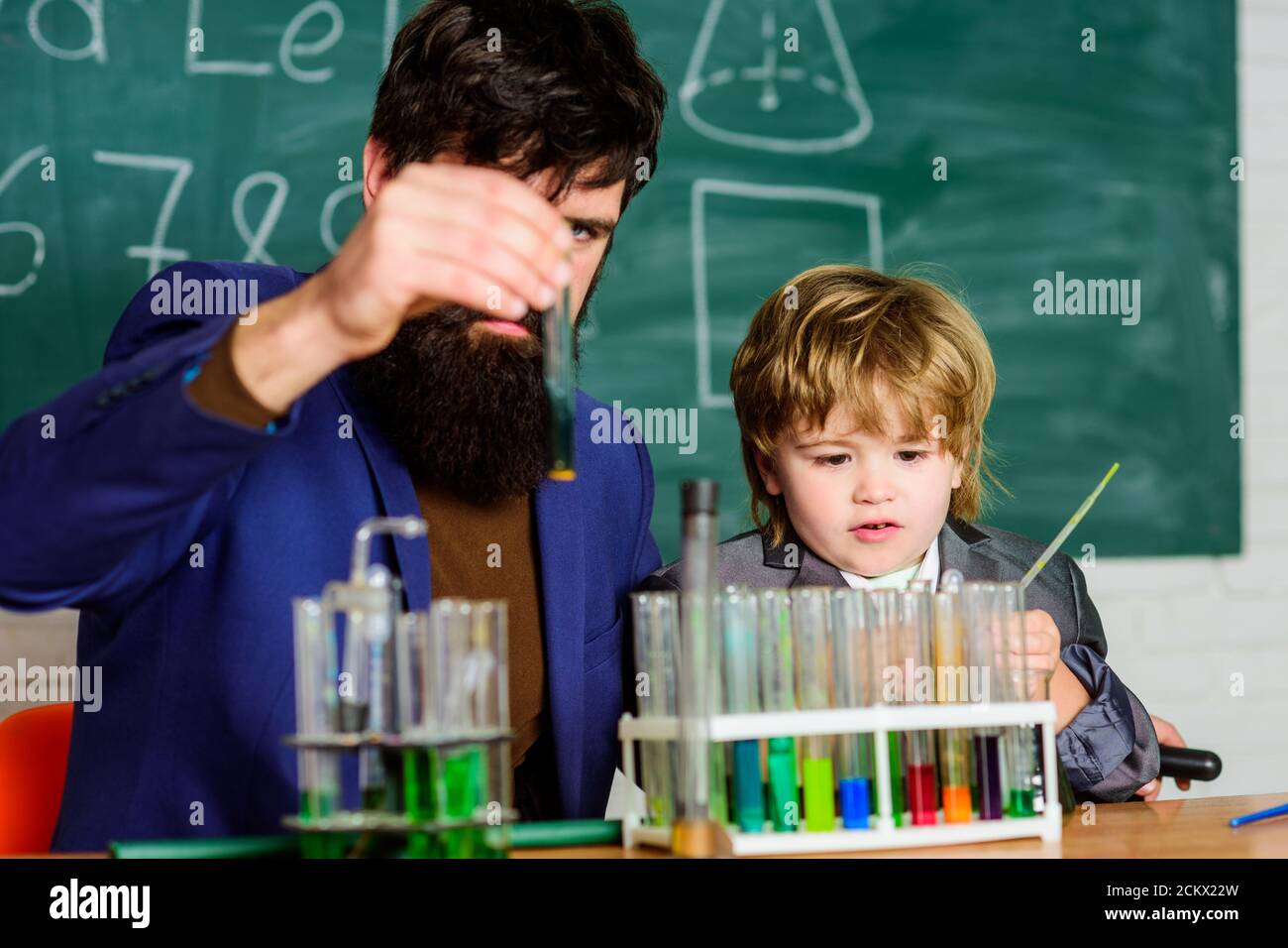 Teacher and child test tubes. School lesson. Perseverance pays off. Chemical experiment. Symptoms of ADHD at school. Educational school program. Schoolboy cute child experimenting with liquids. Stock Photo