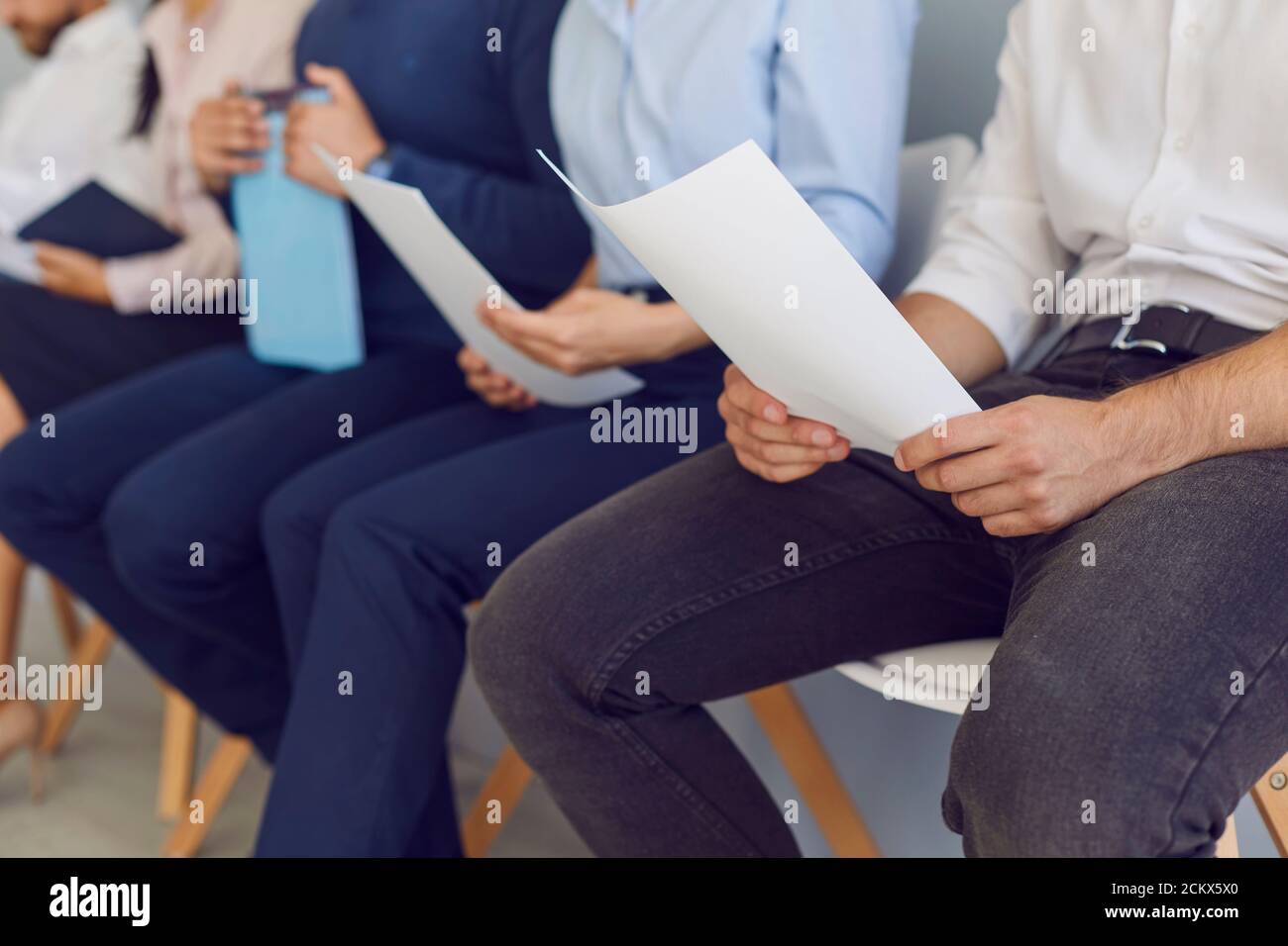 Nervous job applicants waiting for interview and reading their resumes over and over again Stock Photo