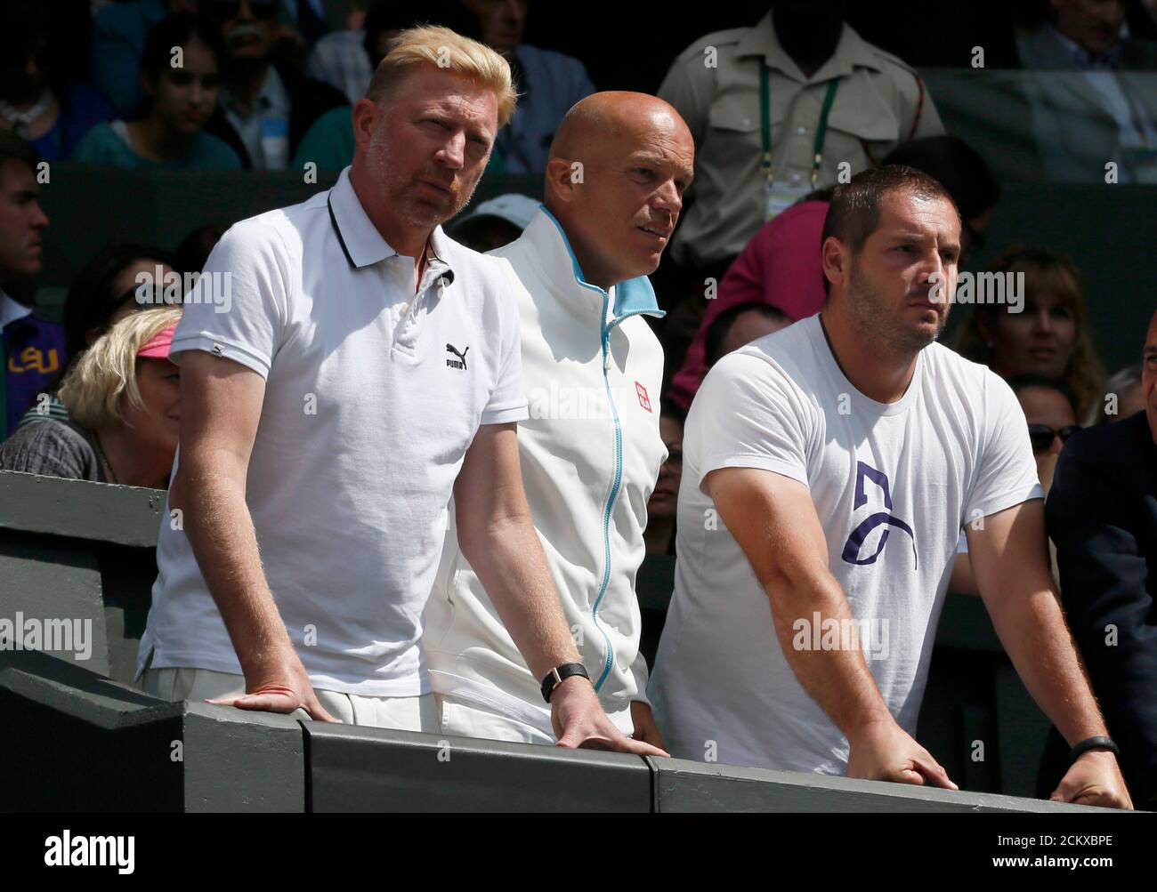 Boris Becker and other members of the coaching team of Novak Djokovic of Serbia stand and react after he fell during his men's singles tennis match against Gilles Simon of France on Centre Court at the Wimbledon Tennis Championships in London June 27, 2014. REUTERS/Stefan Wermuth (BRITAIN  - Tags: SPORT TENNIS) Stock Photo
