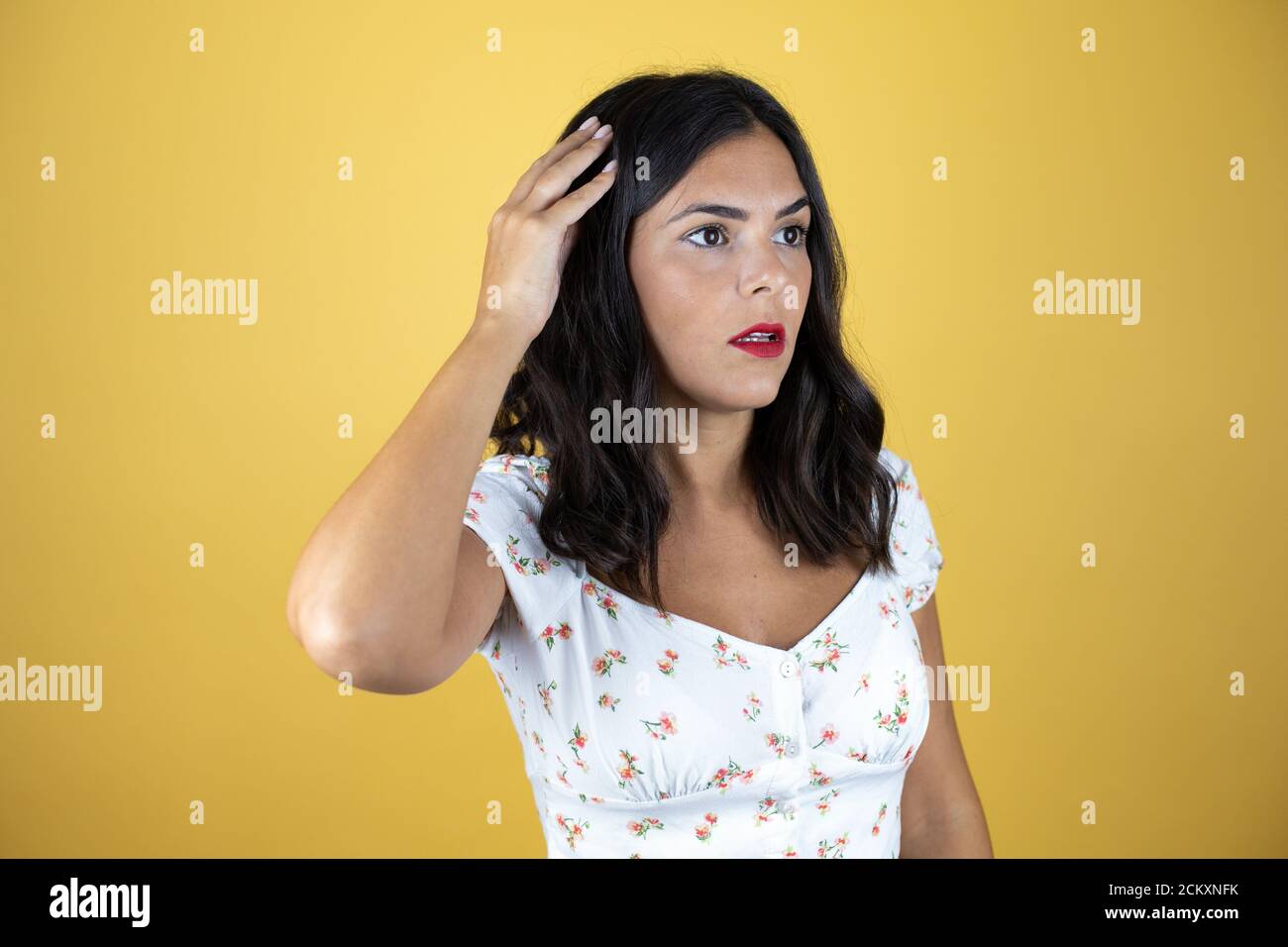Beautiful woman over yellow background smiling and thinking with her ...