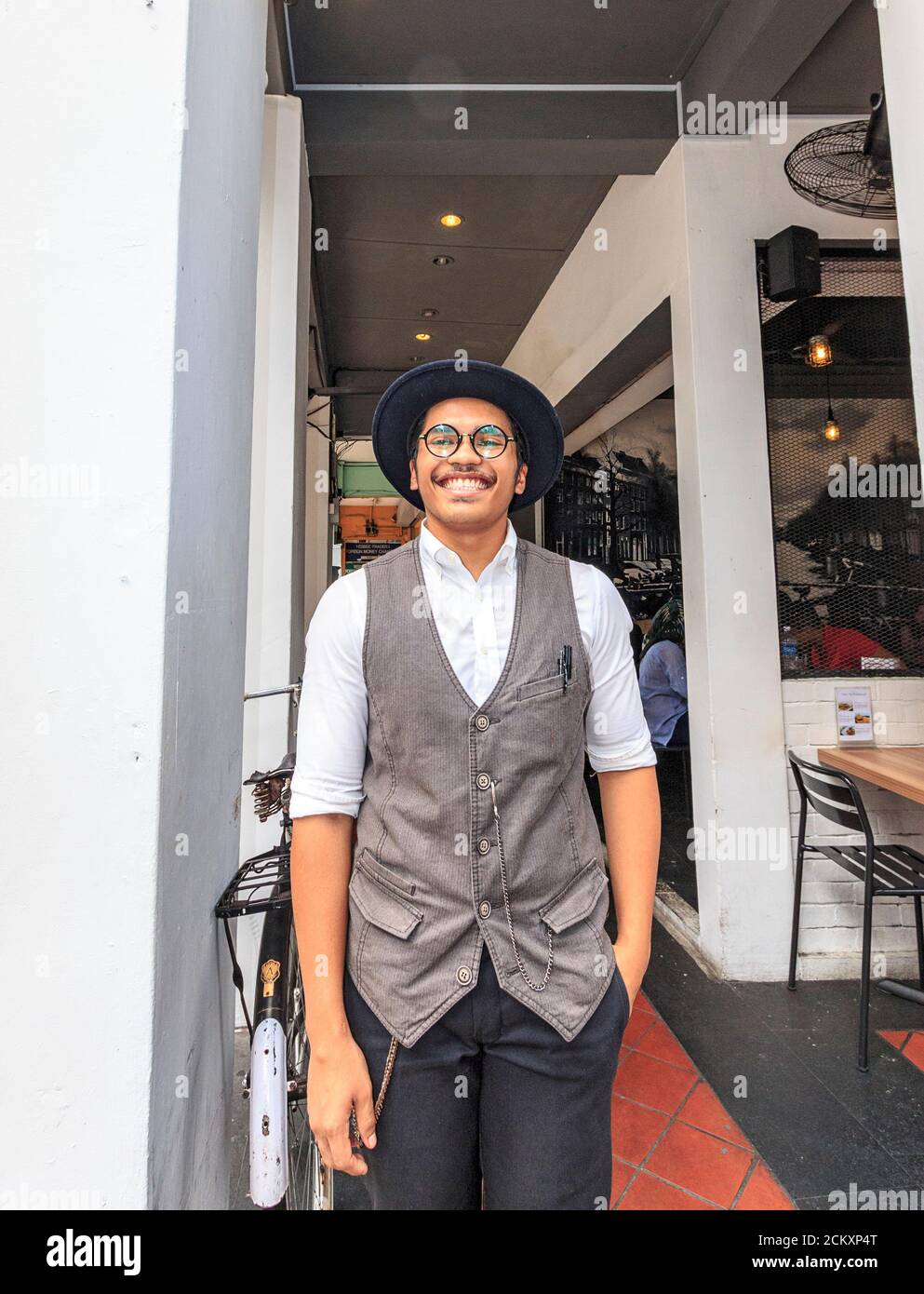 Local waiter, dressed in common clothing for modern Indians living in Singapore, who works in a cafe in Singapore's Little India district. Stock Photo