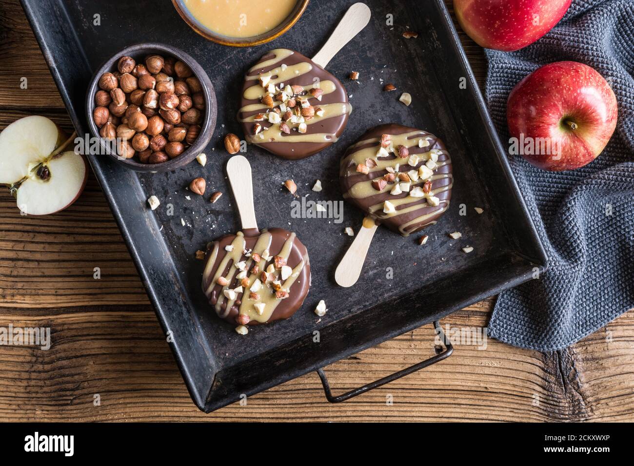 Apple popsicle dipped in chocolate and caramel, studded with chopped hazelnuts Stock Photo