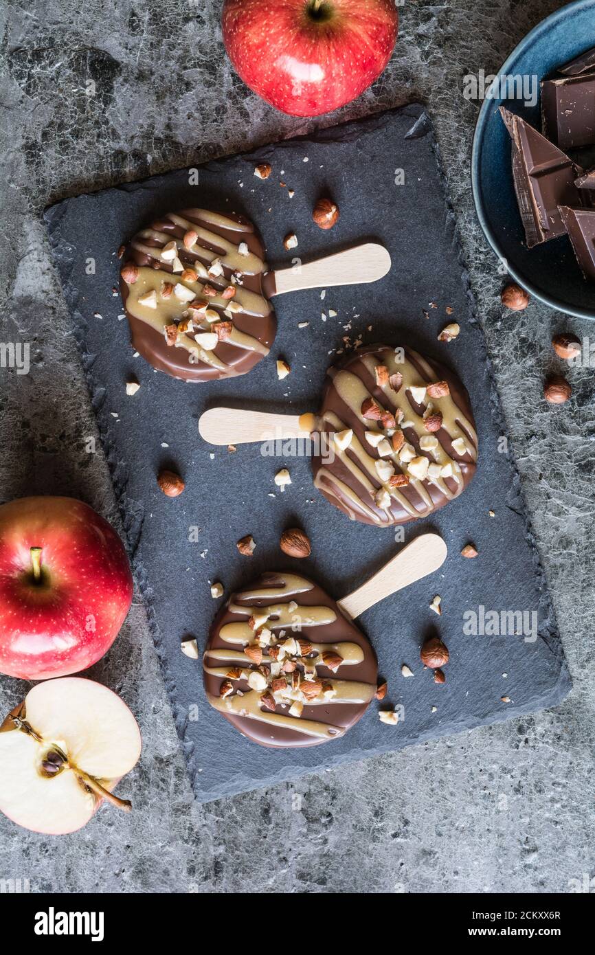 Apple popsicle dipped in chocolate and caramel, studded with chopped hazelnuts Stock Photo