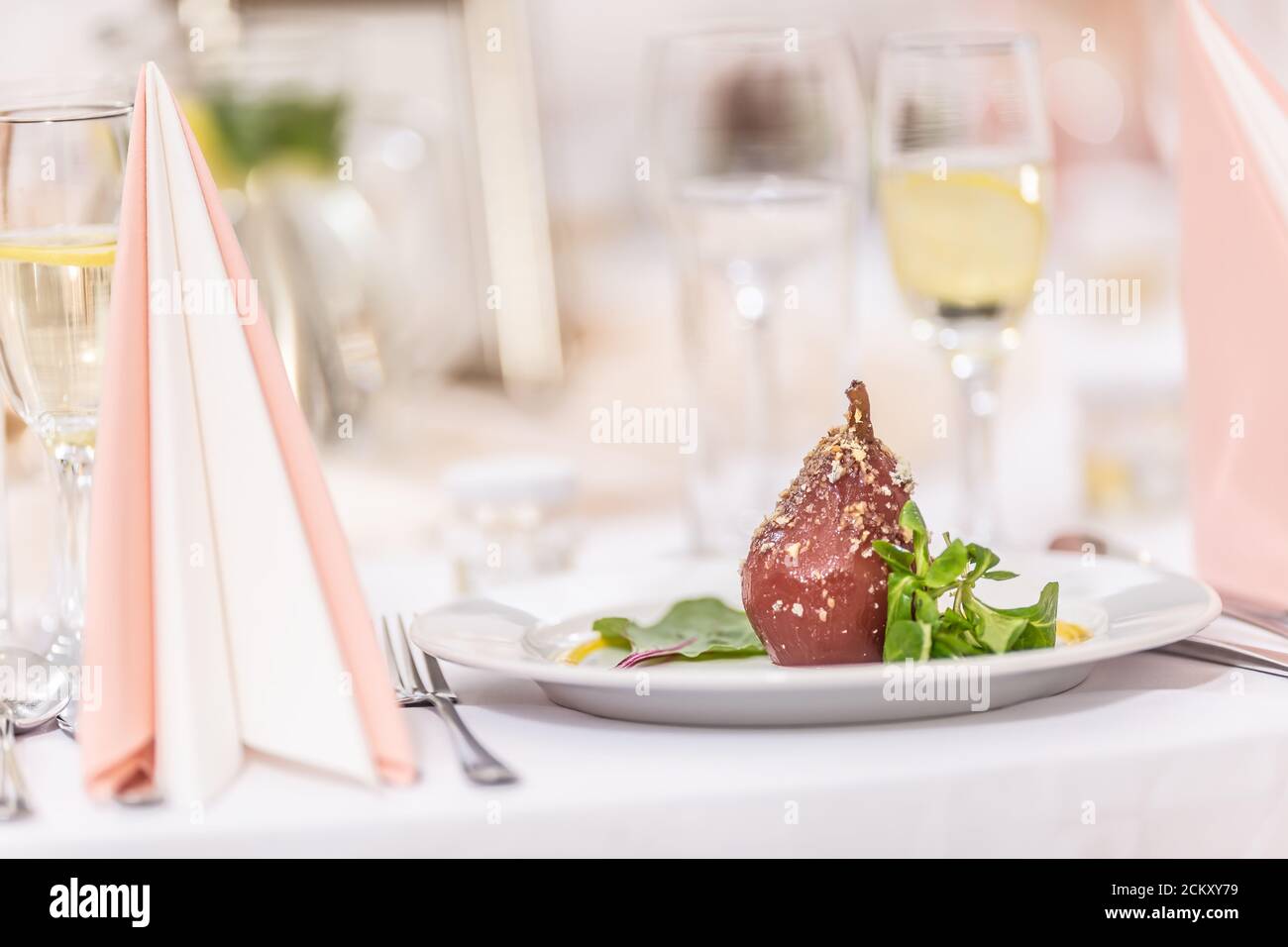 Glazed roasted pears with nut sprinkled on top on a festive table Stock Photo