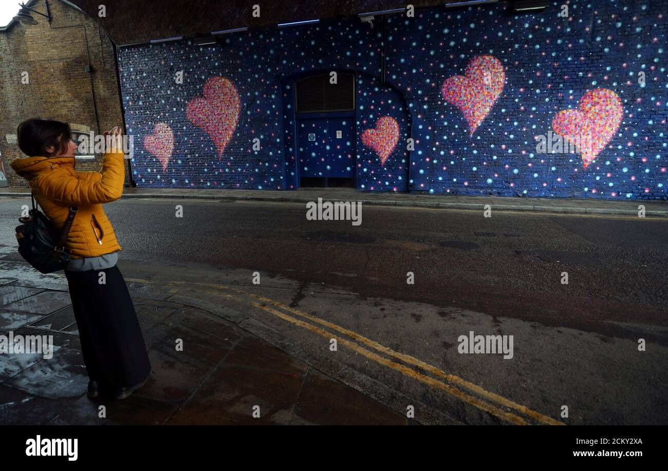 A woman takes a photograph of a mural, by British-born Australian artist James Cochran, painted to commemorate the victims of the London Bridge attack, in London, Britain, April 2, 2018. REUTERS/Hannah McKay Stock Photo