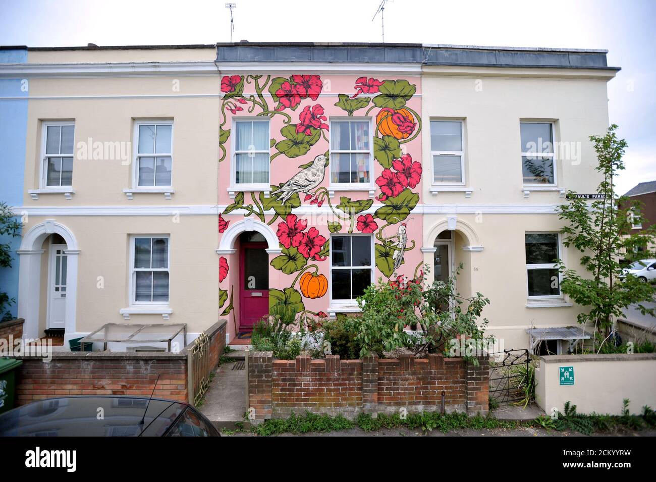 Artist Alex Lucas from Bristol with the house she painted in Cheltenham that coincided with the Cheltenham Paint Festival celebrating street art Stock Photo
