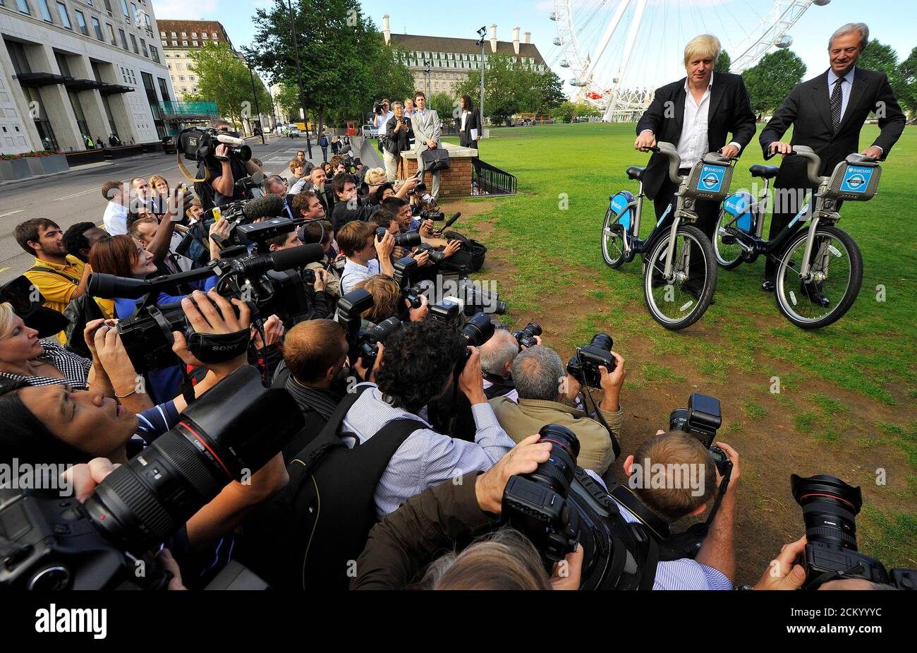 London Mayor Boris Johnson (L) and Chairman of Barclays Marcus Agius pose for photographers with hire cycles beside the London Eye in central London July 30, 2010. A fleet of 6,000 bicycles for hire hit the streets of central London on Friday in a scheme intended to fuel a cycling revolution in the congested capital. The initiative, which follows similar projects in cities including Paris and Montreal, aims to ease overcrowding on London's commuter network, with 400 bicycle 'docking stations' from Notting Hill in the west to the Tower of London in the east. REUTERS/Toby Melville (BRITAIN - Tag Stock Photo
