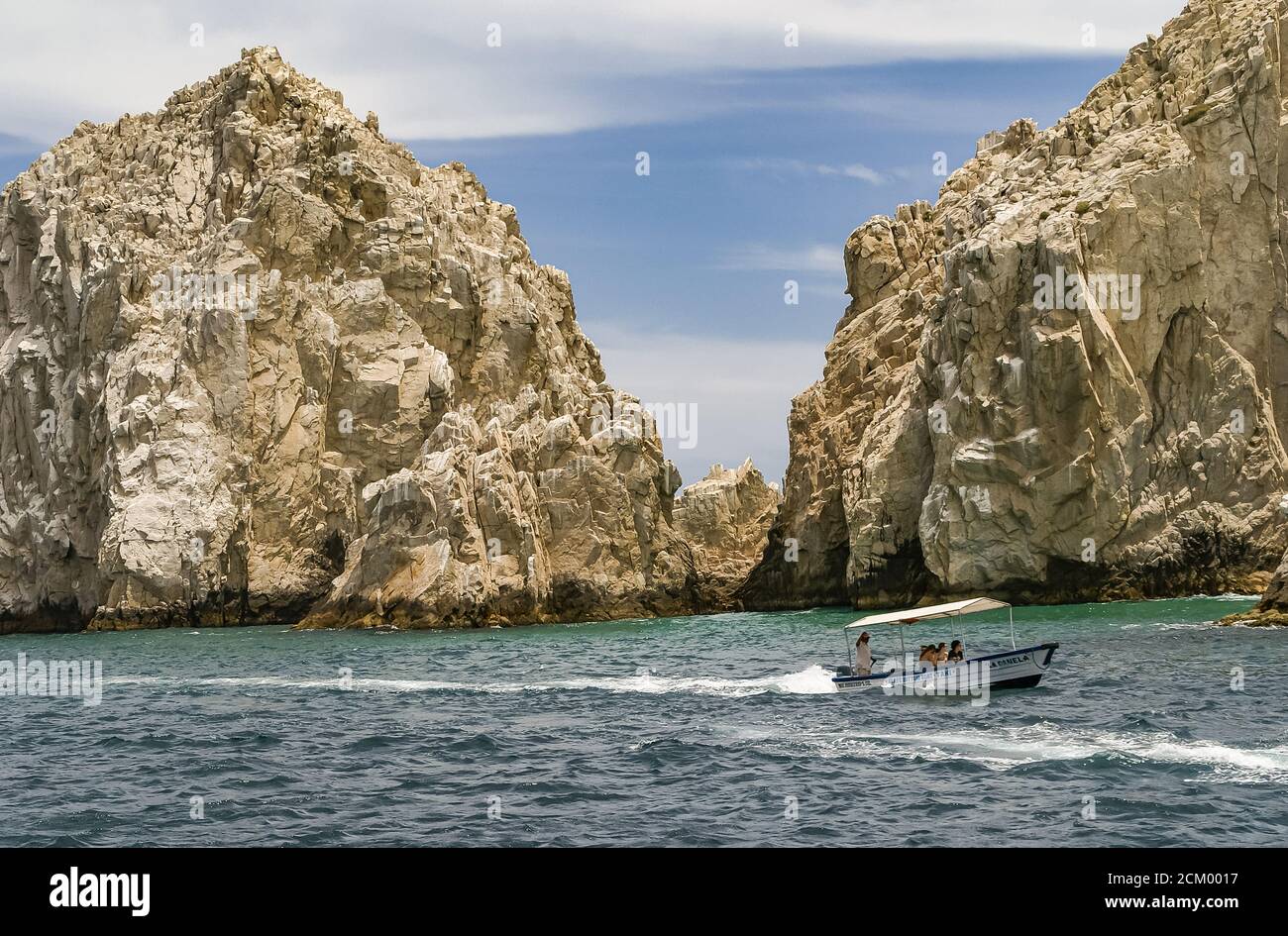 Cabo San Lucas, Mexico - April 22, 2008: South end of Baha California. Closeup of couple of beige rocks in a gray-greenish ocean under blue cloudscape Stock Photo