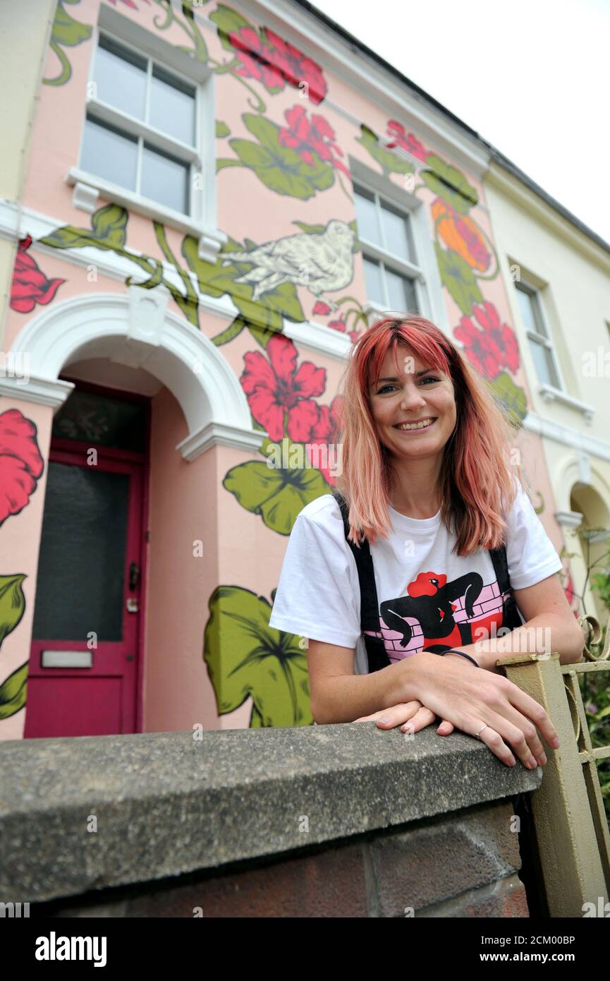 Artist Alex Lucas from Bristol with the house she painted in Cheltenham that coincided with the Cheltenham Paint Festival celebrating street art Stock Photo