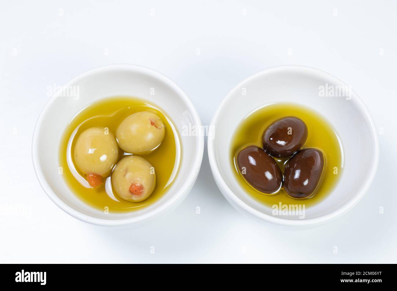 Black and green olives in small bowl with an oil and herb dressing. One  olive is selected with a wooden pick Stock Photo - Alamy