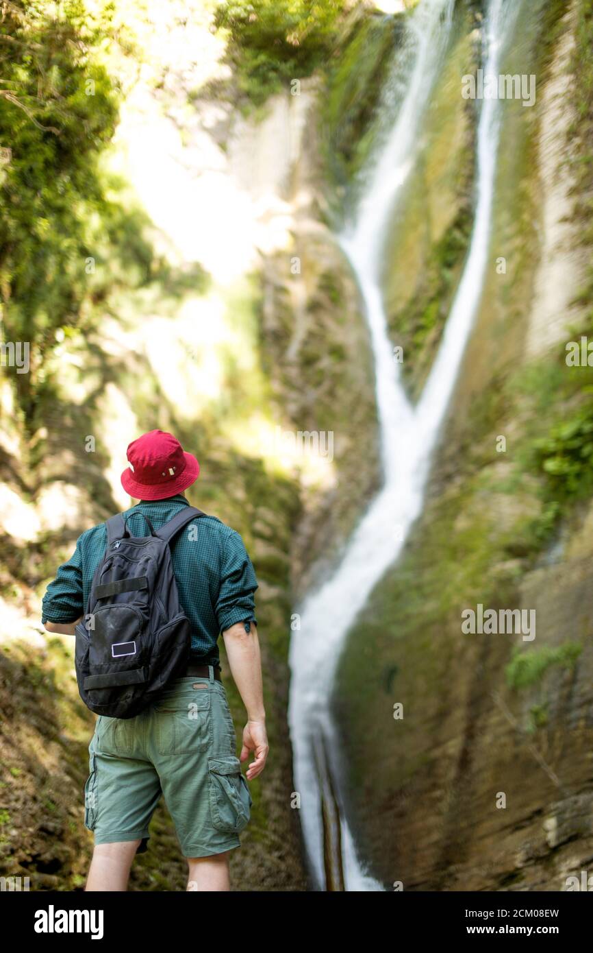 Young male caucasian traveler in red hat and summer hiking outfit