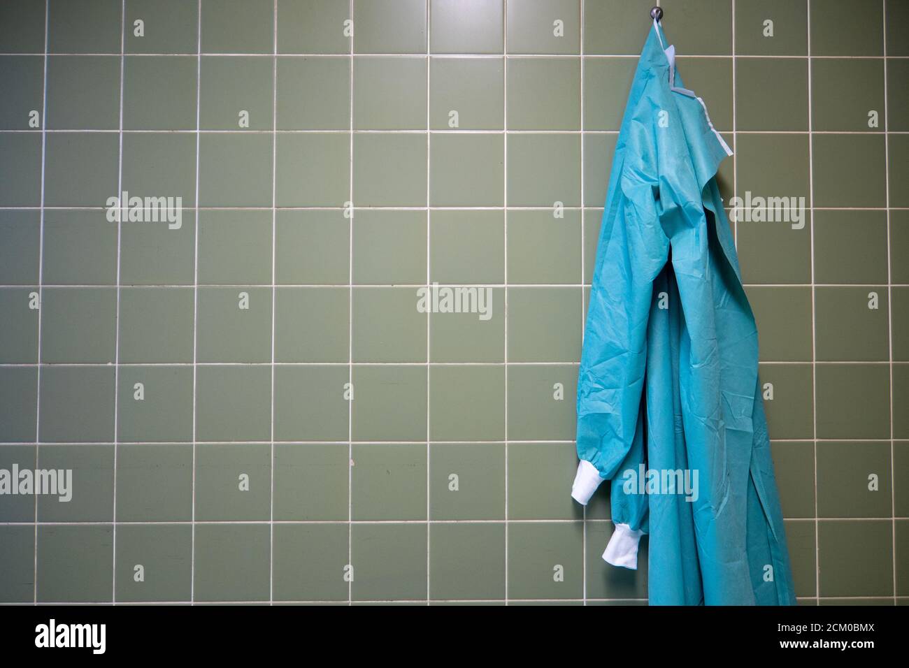 a green surgical gown is hanging on a wall in an operating room Stock Photo