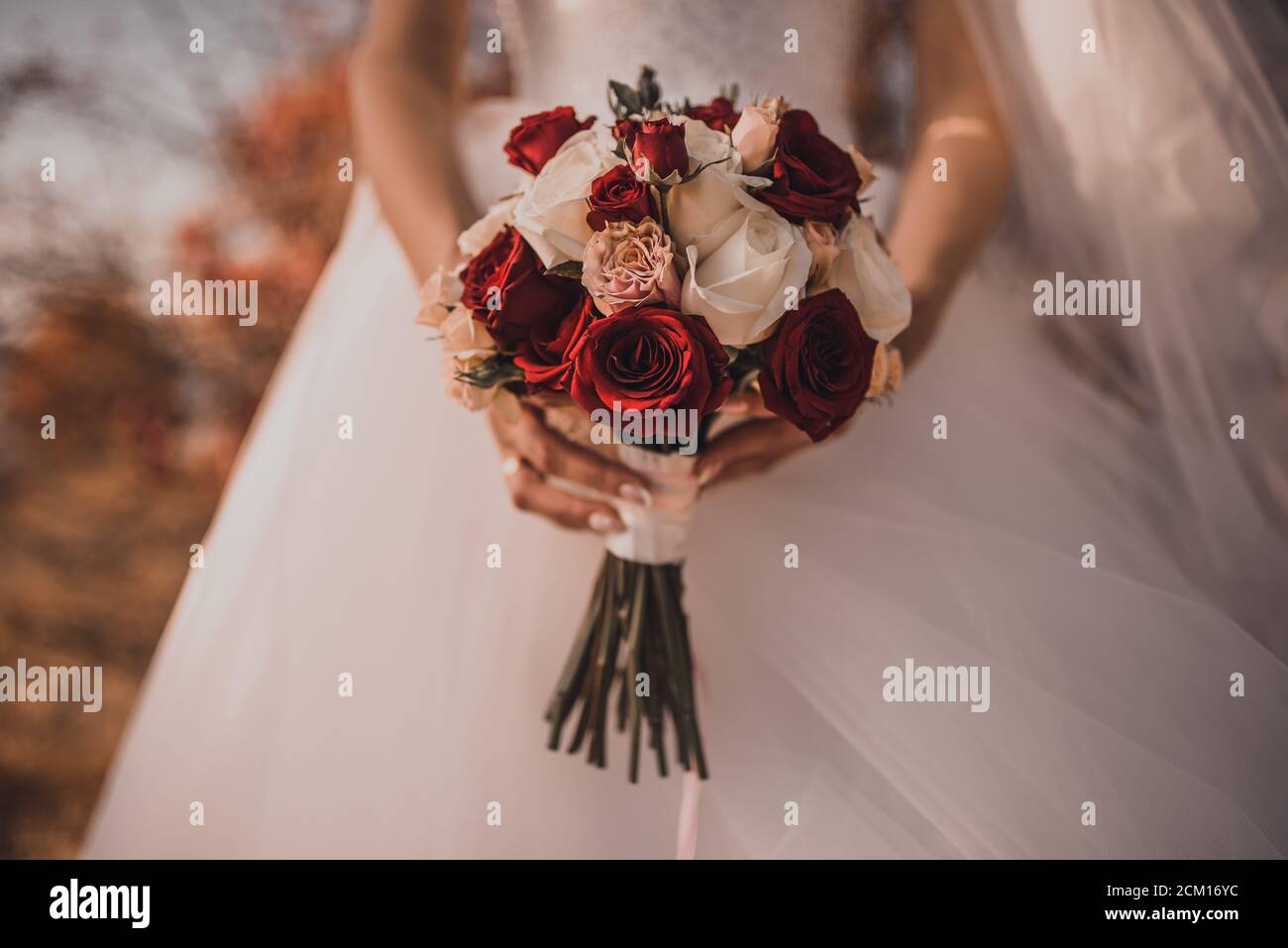 A bride in a white wedding dress holds a bouquet Stock Photo - Alamy