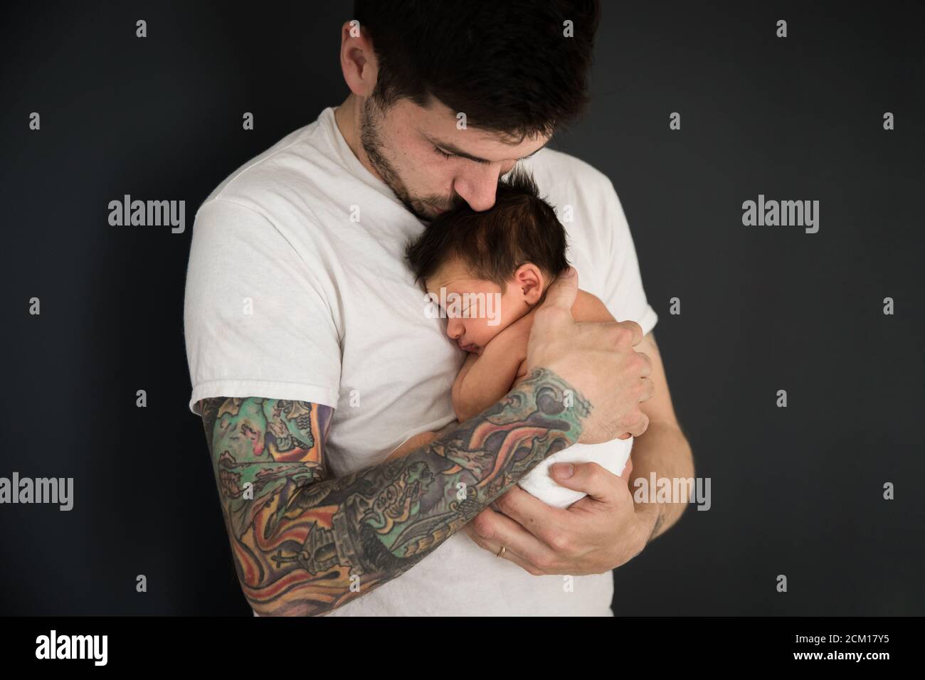 Tattooed Millennial Dad Kisses Newborn Son Wearing Diaper Stock Photo