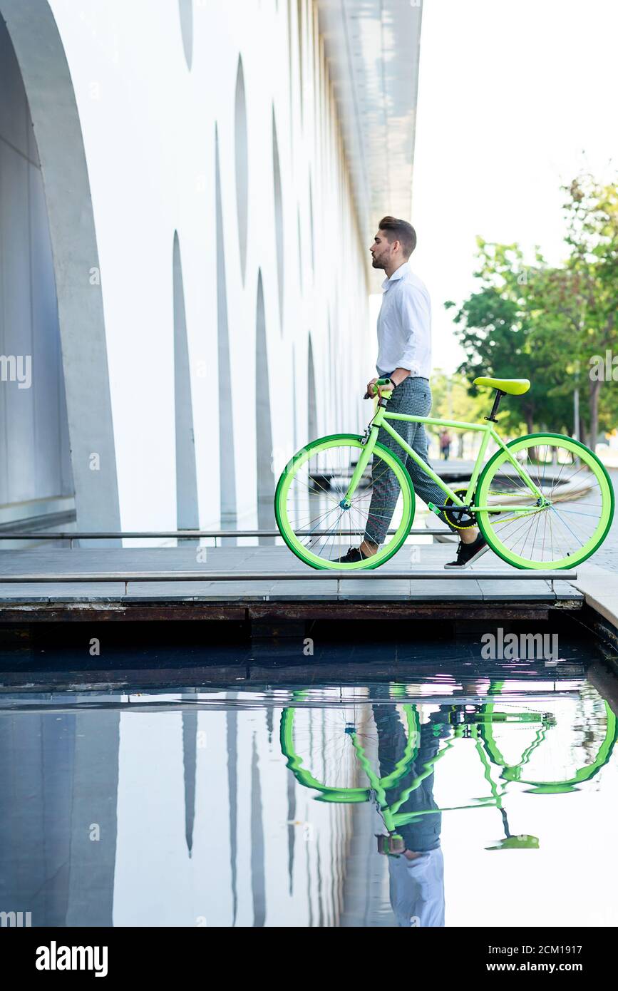 Side view of a young bearded man walking with fixie bike Stock Photo