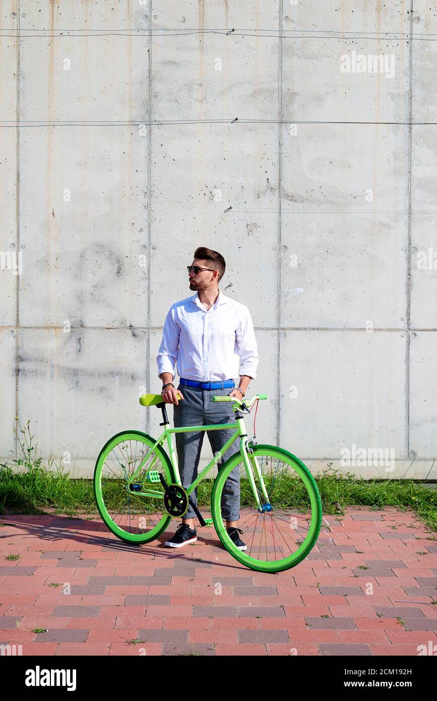 Young bearded man with sunglasses standing with bike outdoors Stock Photo