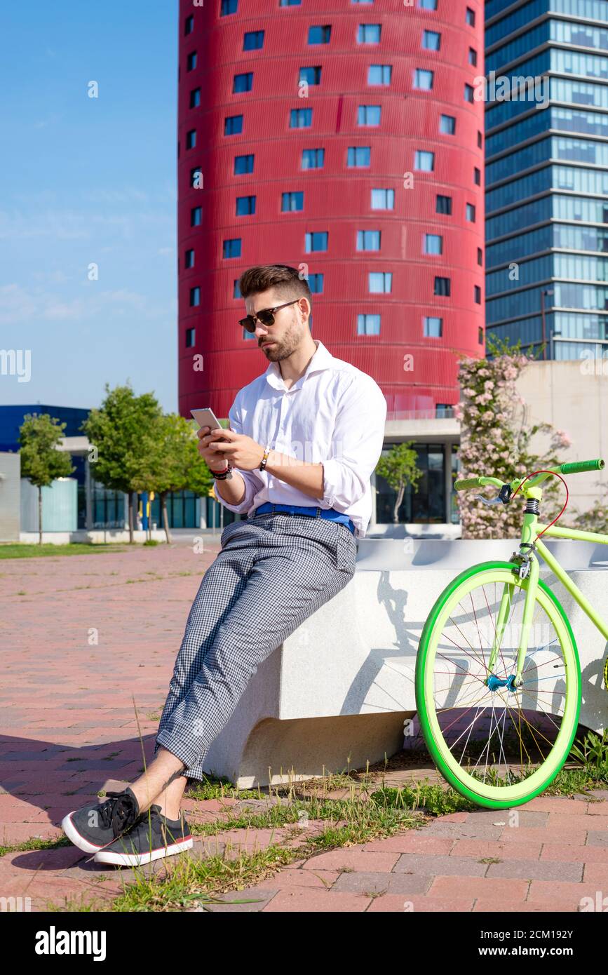 Outdoor portrait of handsome young man with mobile phone and fixed gear bicycle in the street. Stock Photo
