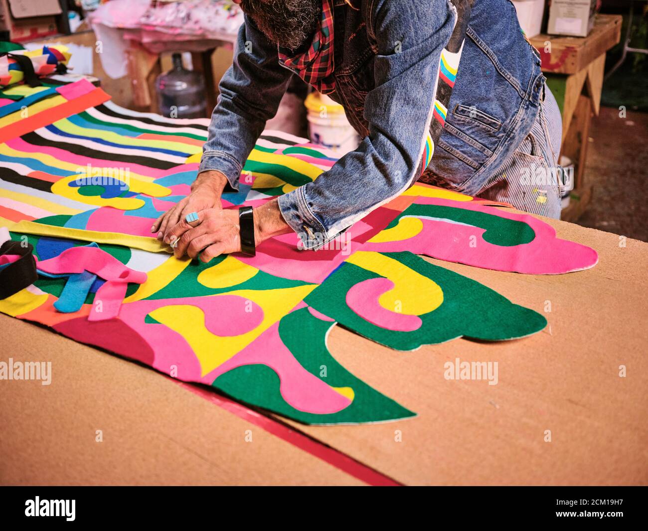 An artist works on a giant cloth tapestry in the their art studio Stock