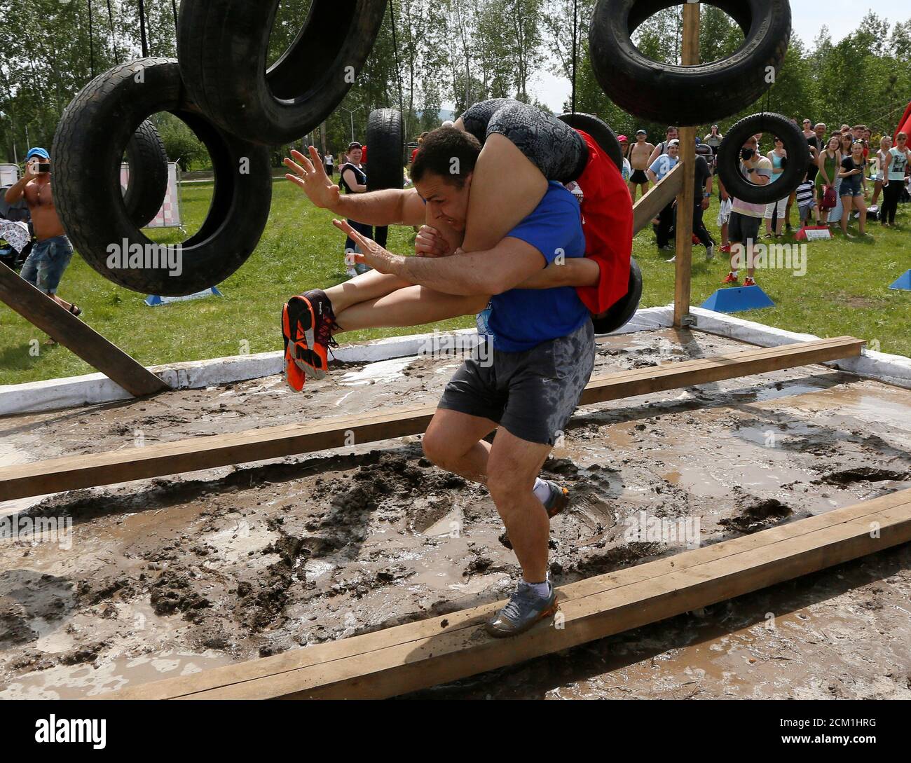 A man carries his wife over an obstacle while racing in the Wife Carrying competititon to mark the City Day in Krasnoyarsk, Siberia, Russia, June 10, 2017. Picture taken June 10, 2017. REUTERS/Ilya Naymushin Stock Photo