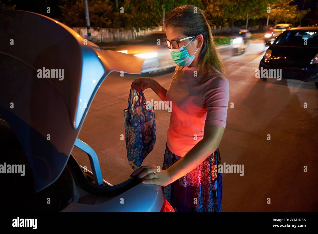A woman put her belonging to the car trunk after shopping during COVID Stock Photo