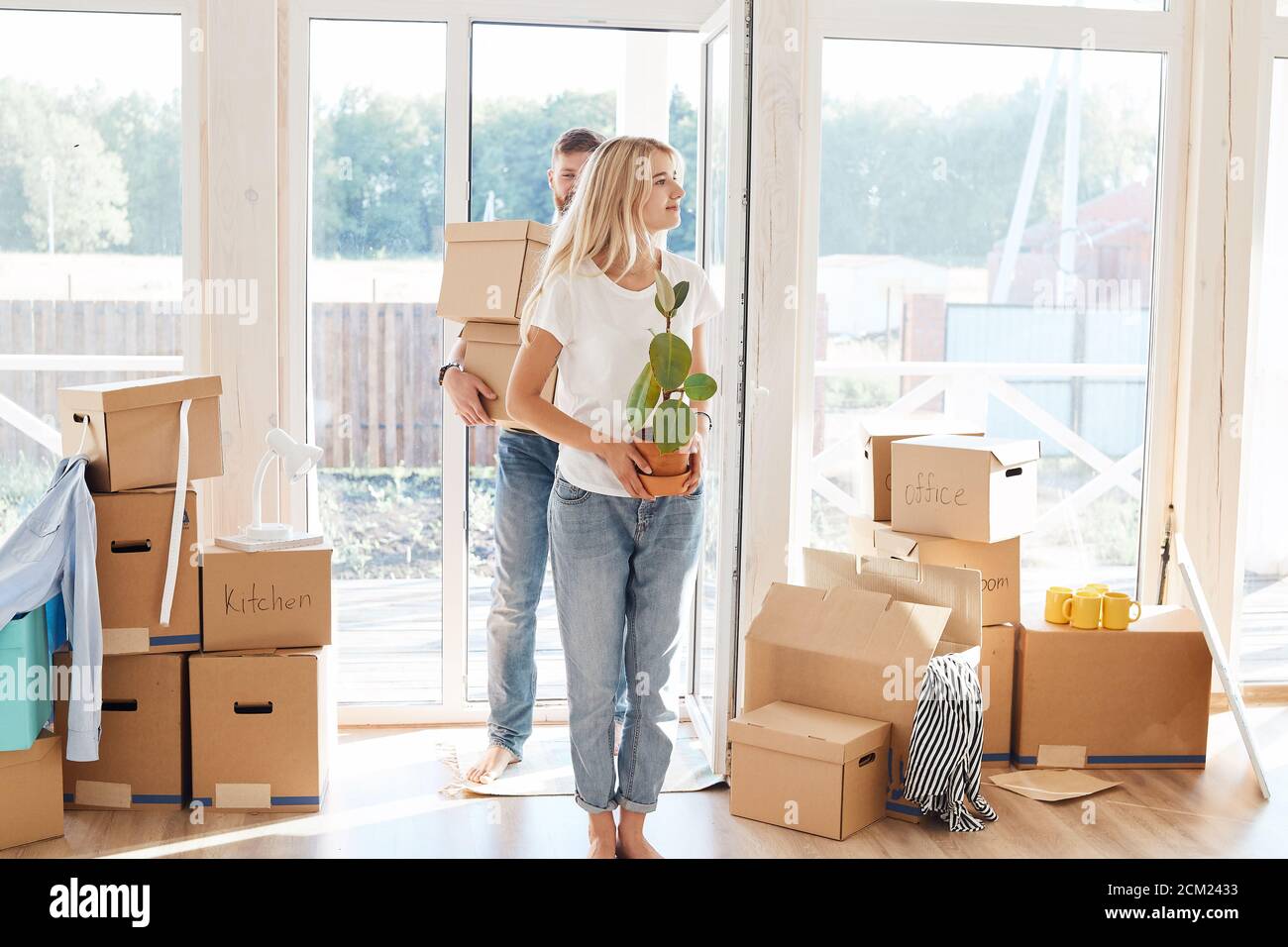 Happy young Couple Carrying Cardboard Boxes Into New Home On Moving Day ...