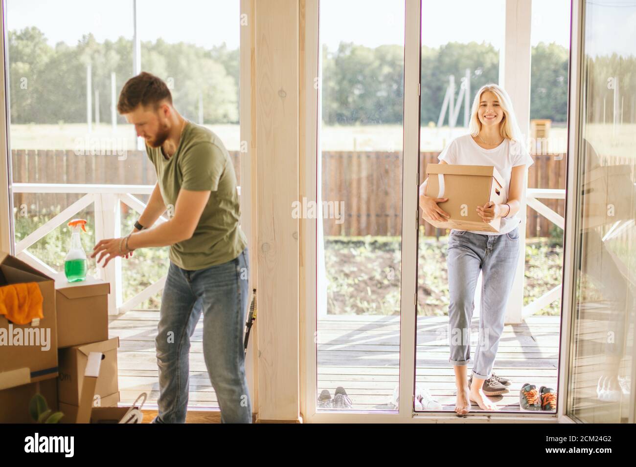 Happy young Couple Carrying Cardboard Boxes Into New Home On Moving Day ...