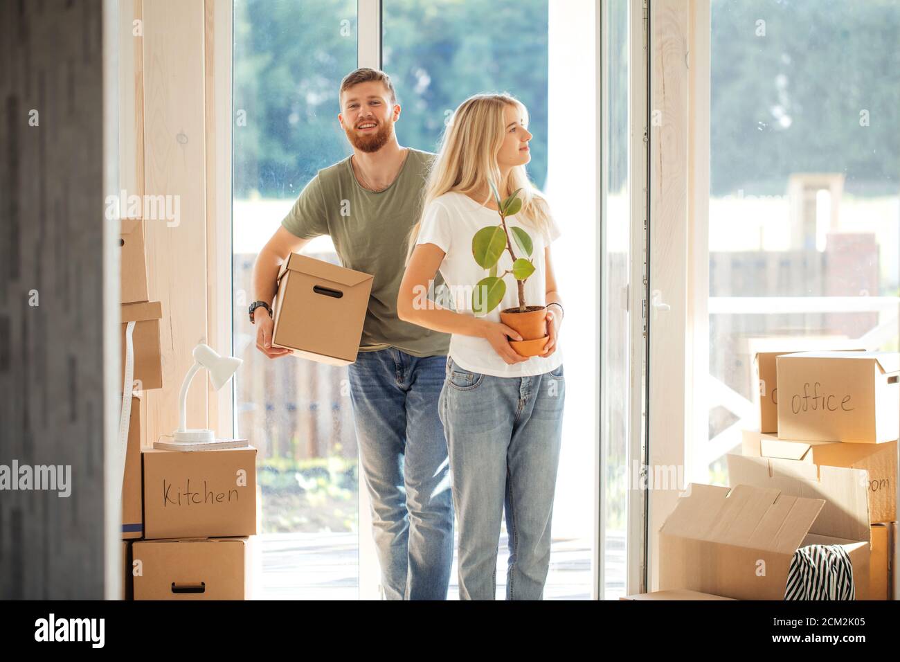 Happy young Couple Carrying Cardboard Boxes Into New Home On Moving Day ...